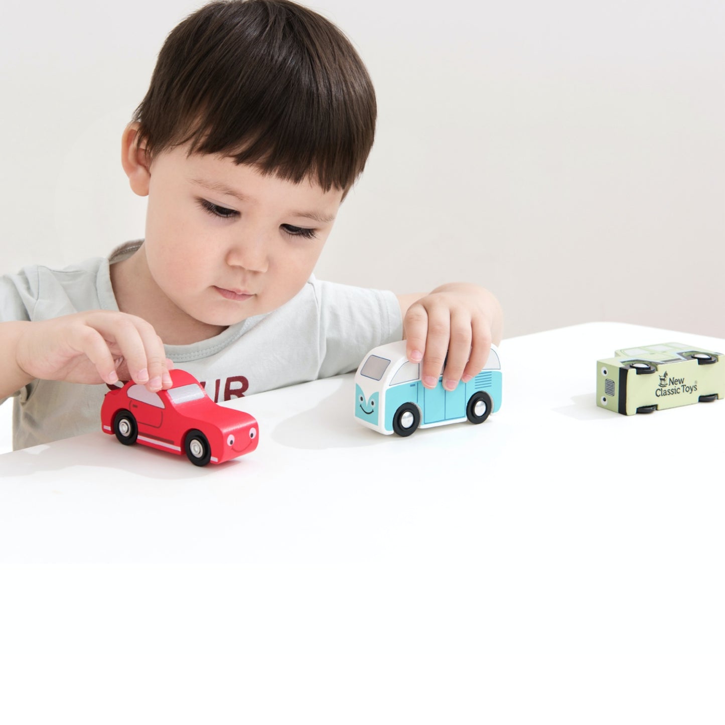 New Classic Toys Wooden Shape Sorter Truck | Baby & Toddler Activity Wooden Toy | Lifestyle - Boy Playing with Two Cars on Table | BeoVERDE.ie